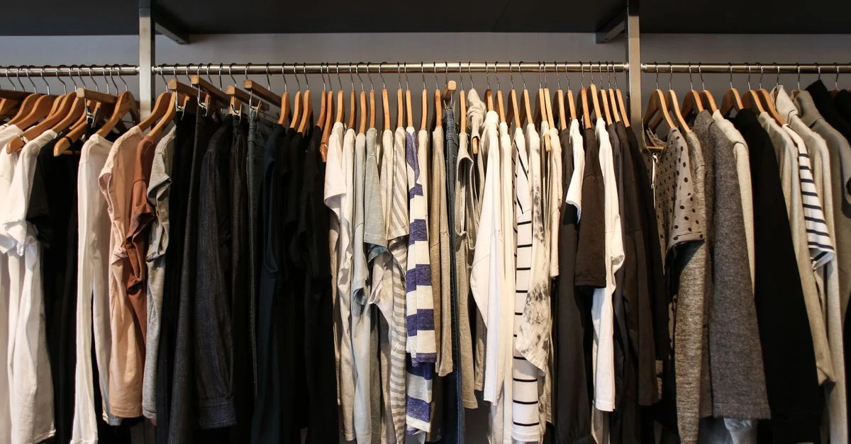 Large gamme de vêtements à la mode sur des cintres en bois dans un cadre de boutique.