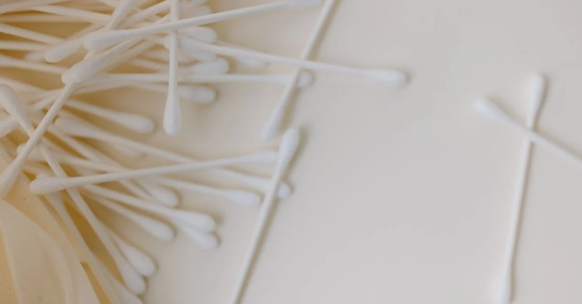 Un gros plan détaillé de plusieurs coton-tiges dispersés sur une surface lisse et neutre, mettant en avant la propreté et l'hygiène.