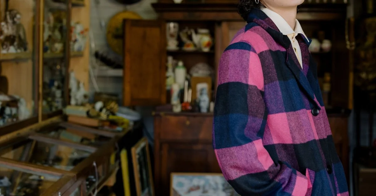 Une personne en manteau à carreaux explore une boutique d'antiquités remplie d'objets vintage.
