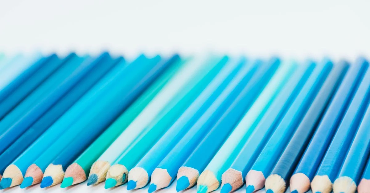 Une variété de crayons de couleur bleus disposés en ligne, idéaux pour des thèmes artistiques et créatifs.