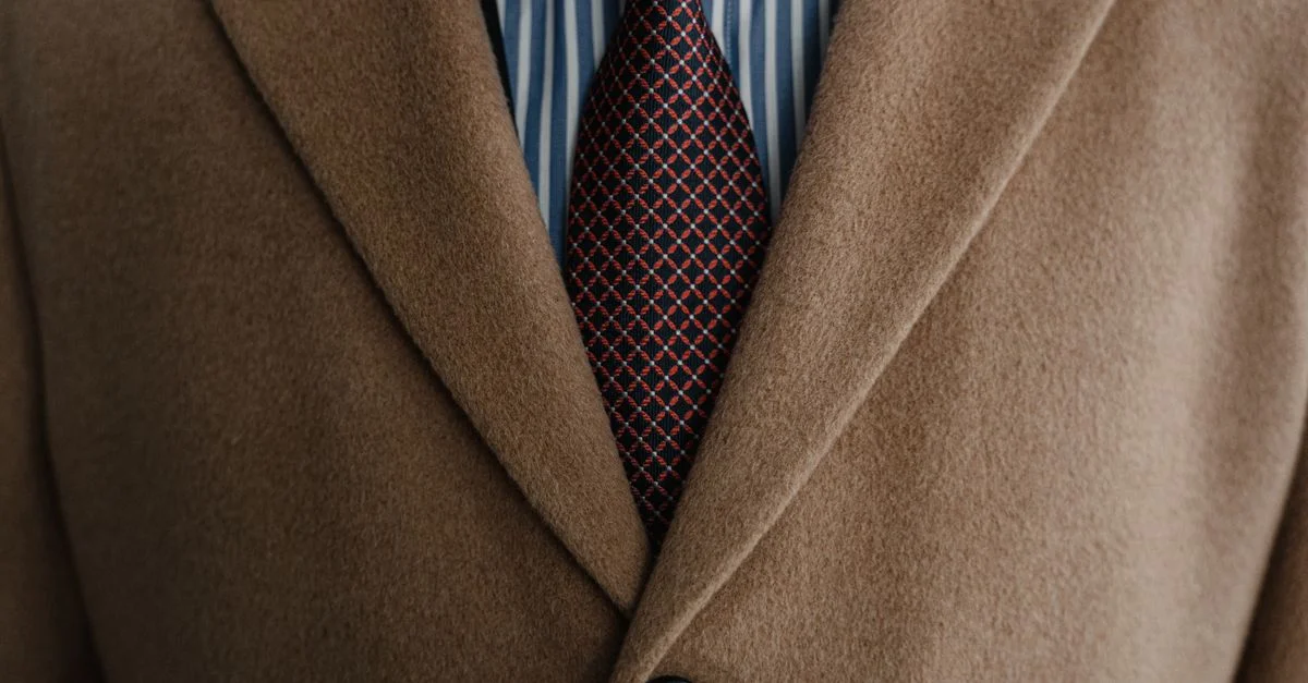 Gros plan sur un élégant manteau en laine marron sur une chemise rayée et une cravate à motifs.