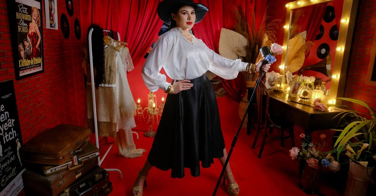 Artiste élégante dans un décor de cabaret vintage avec rideaux rouges et miroir de courtoisie.
