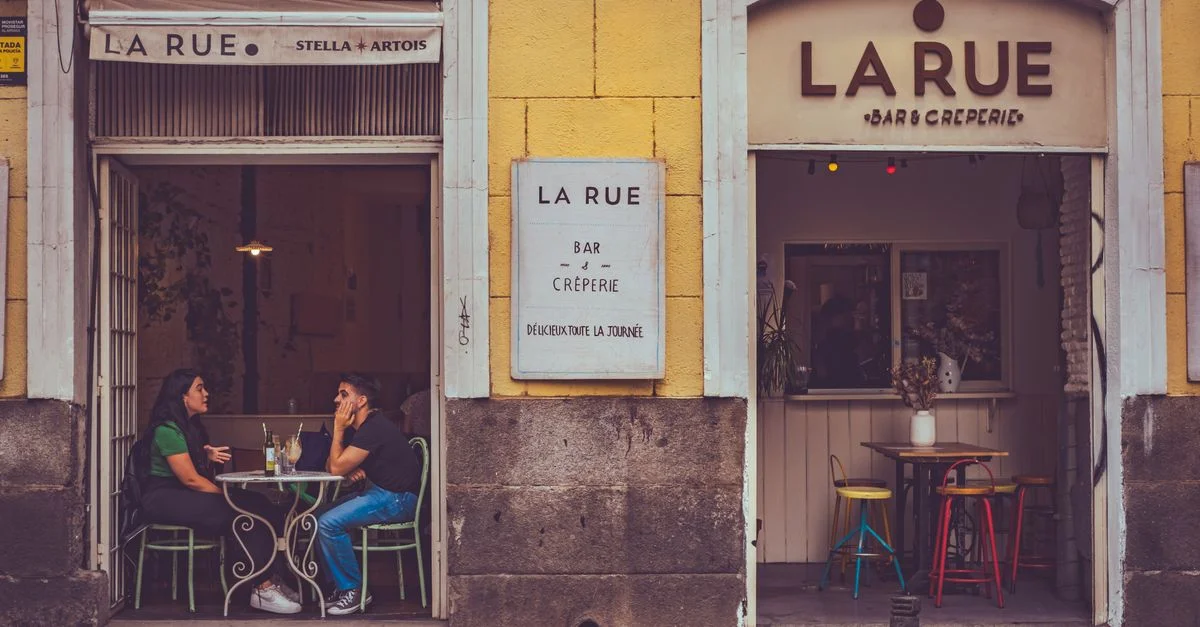Ambiance décontractée en terrasse à Madrid avec deux personnes savourant une boisson.